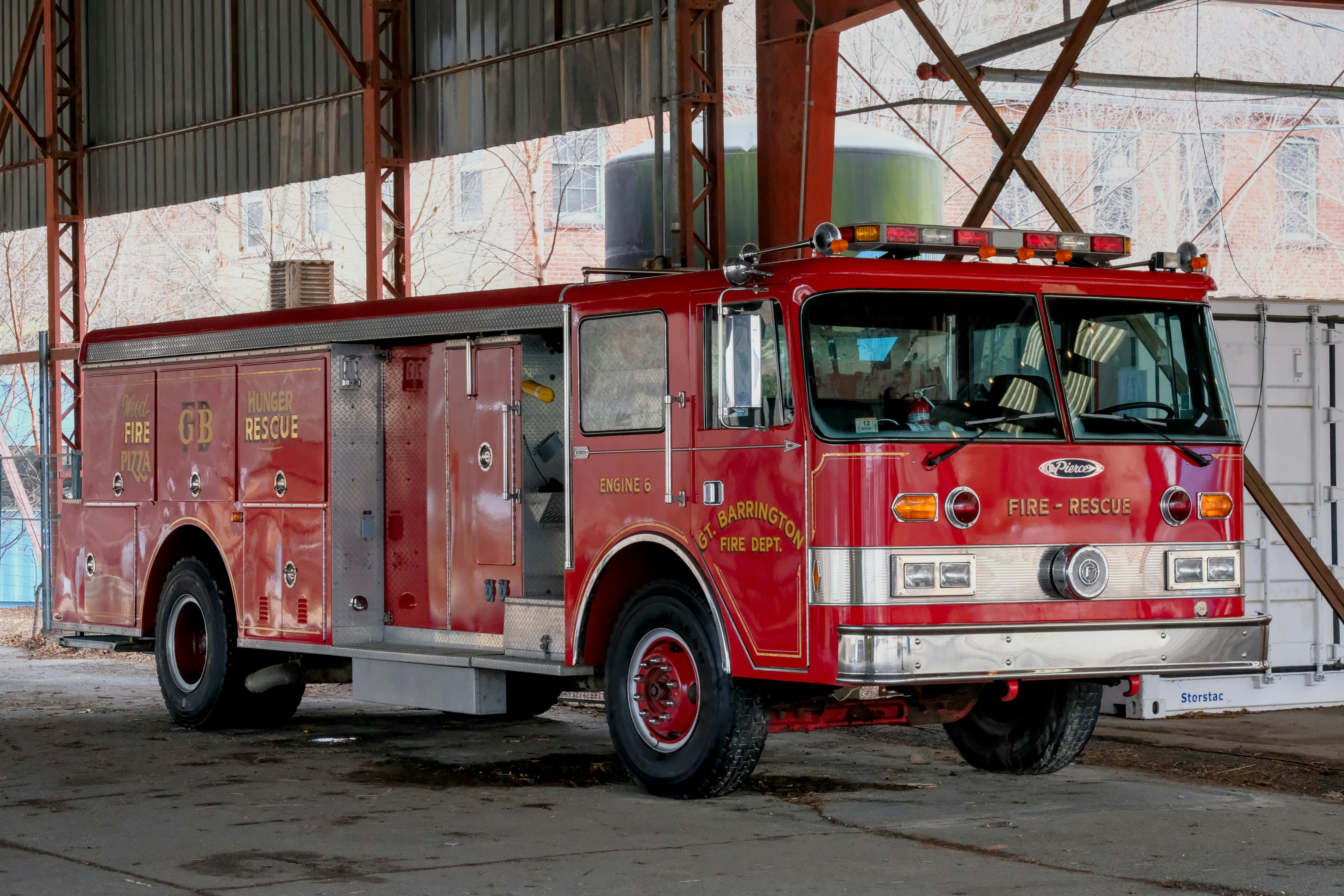 Vintage red fire truck indoors under industrial structure.