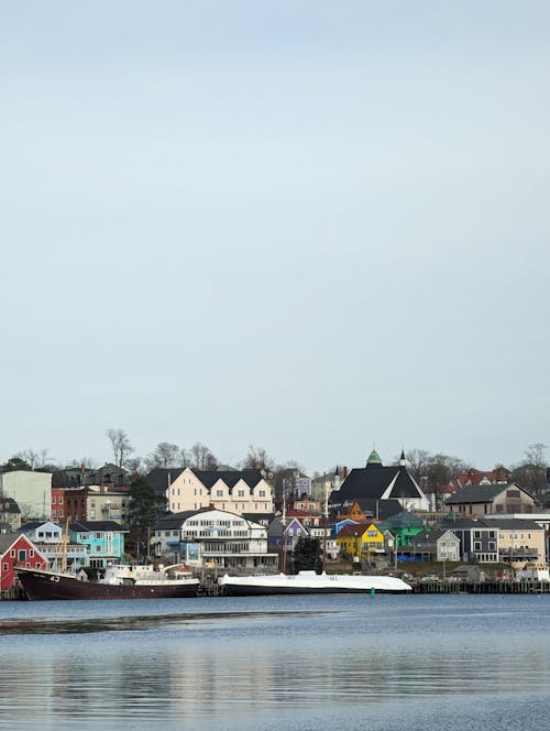 White and Gray Buildings near Body of Water under Gloomy Sky