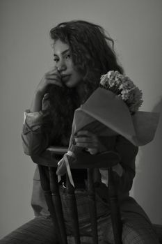Elegant black and white portrait of a woman seated with a bouquet in hand.