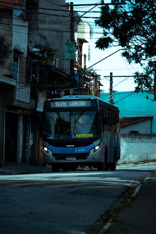 Free A bus drives through a narrow urban street, showcasing city transportation. Stock Photo