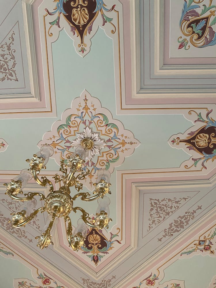 Golden Chandelier Hanging On Ornate Ceiling