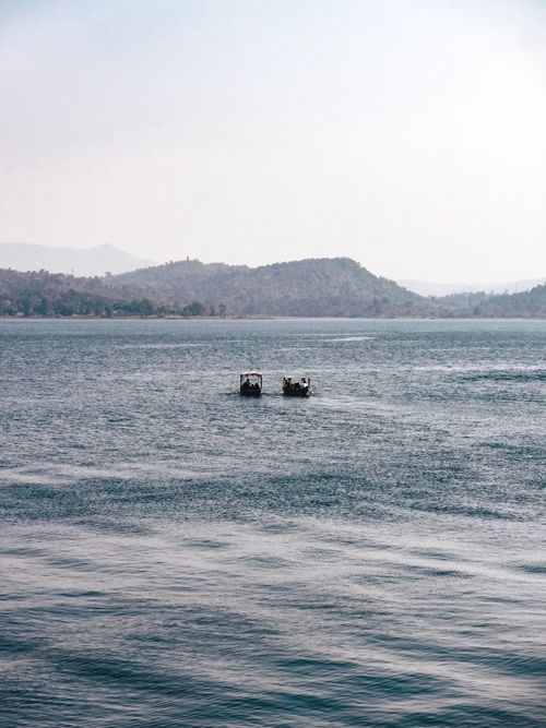 Free Two boats on a tranquil lake with distant hills under a clear sky. Stock Photo