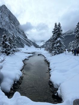 Snow-covered Lake Louise with surrounding mountains and icy waters in winter, Canada.