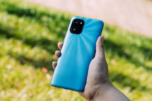 Free Close-up of a hand holding a blue smartphone outdoors on a sunny day. Stock Photo