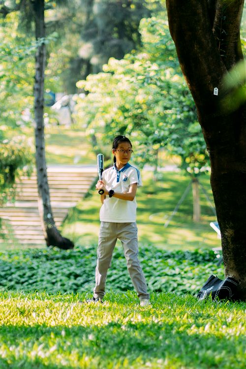 Free Asian girl prepares to hit a baseball in a sunny green park, enjoying a leisure activity. Stock Photo