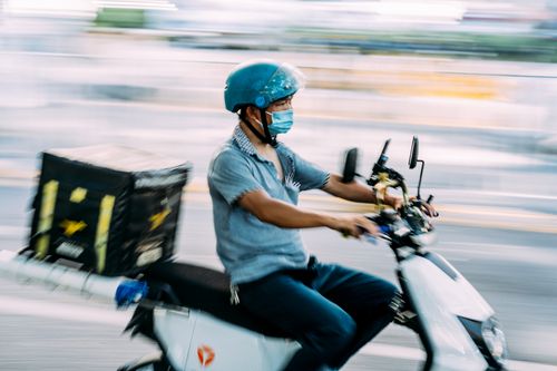 Free Motorcycle courier with a delivery box, riding quickly through the city. Stock Photo
