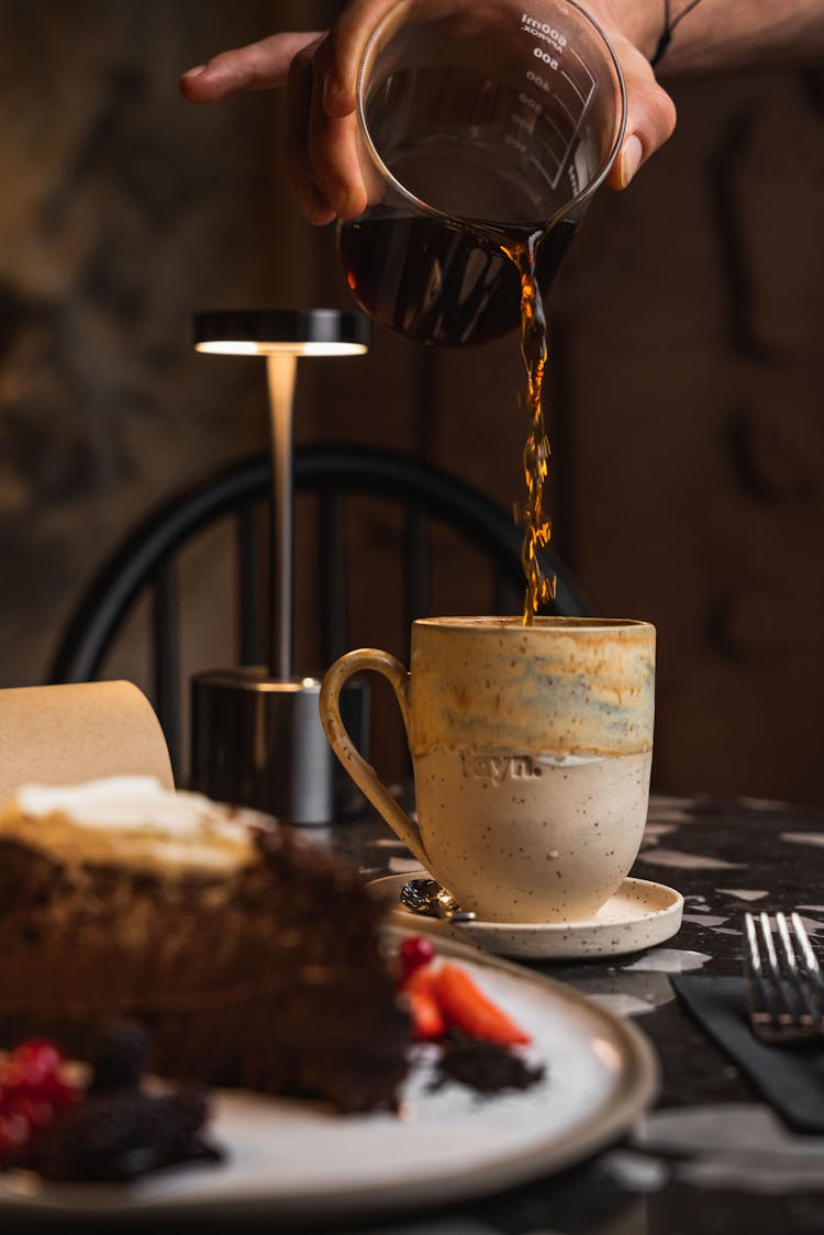 A Person Pouring Coffee Into A Mug