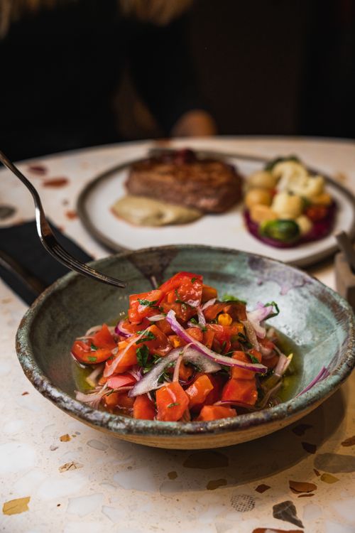 Free Colorful tomato salad with onions and herbs, served as part of a gourmet meal on a table setting. Stock Photo