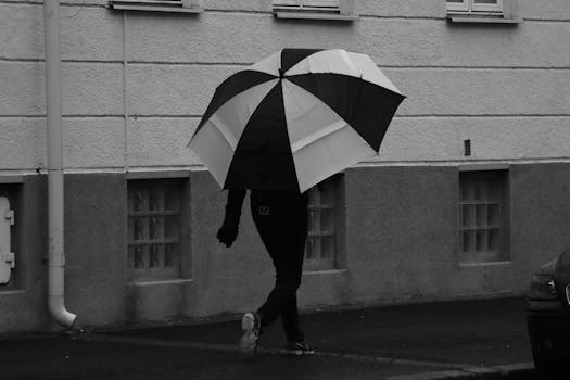 A person walks in the rain with a striped umbrella on a city street in Denmark.