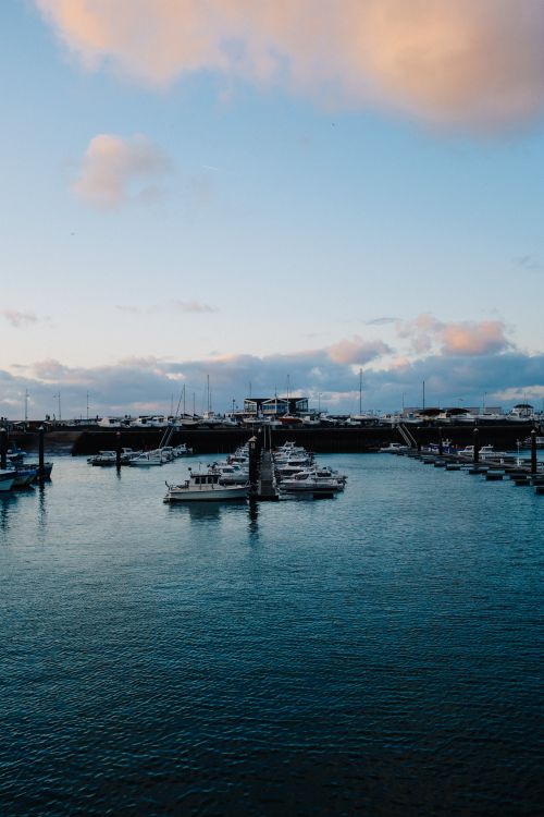 Free Tranquil scene of boats moored at a harbor during sunset with cloudy sky. Stock Photo