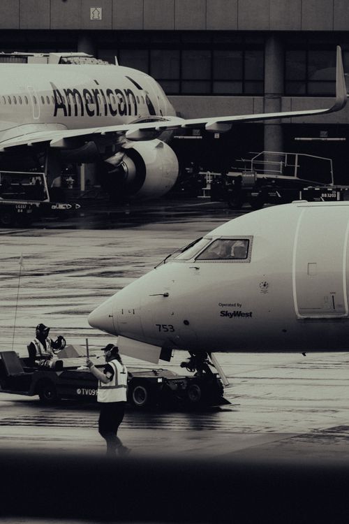 Free Black and white image of airplanes on runway with workers, showcasing a busy airport atmosphere. Stock Photo