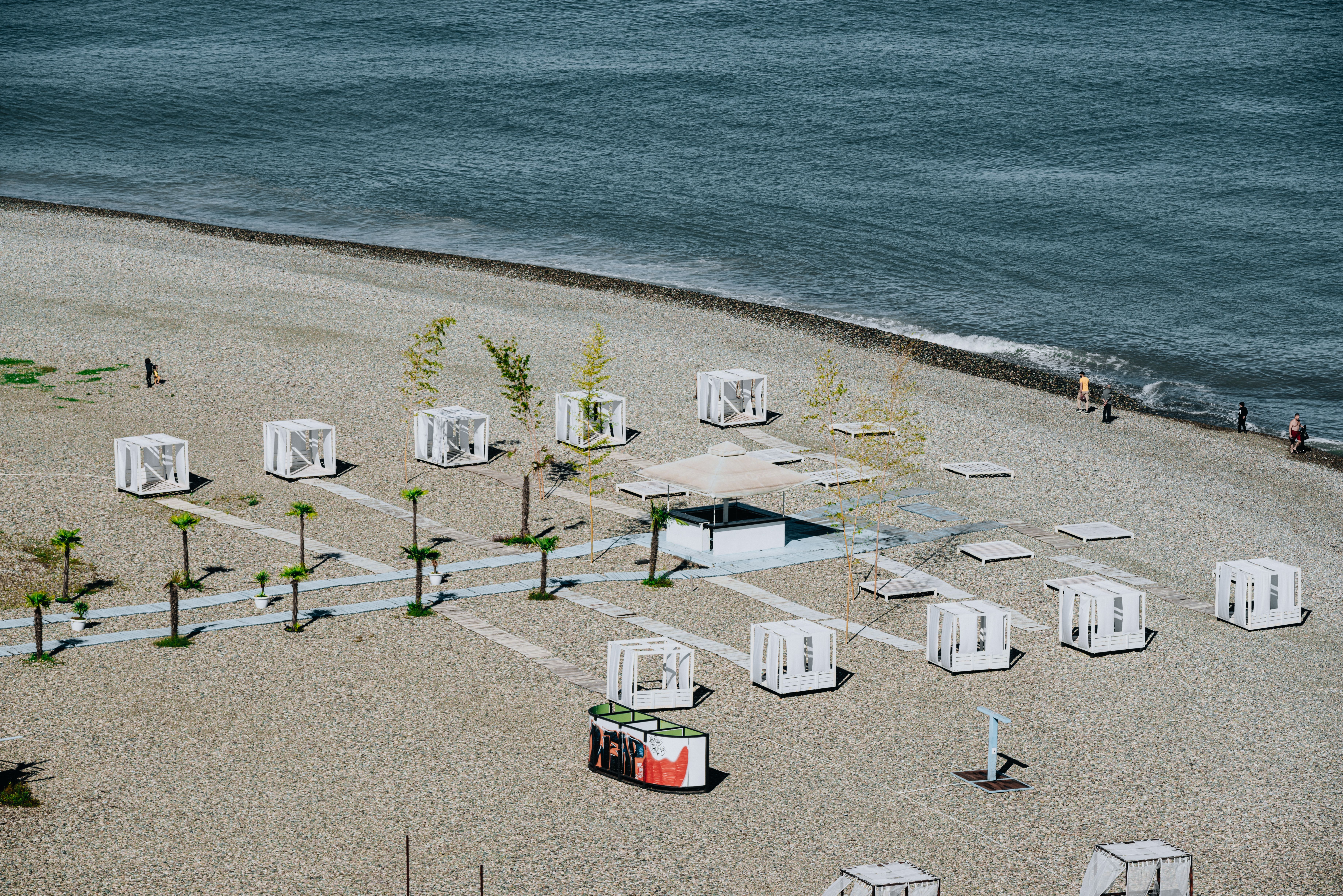 Aerial view of modern structures on a pebble beach by the sea, capturing leisure and architecture.