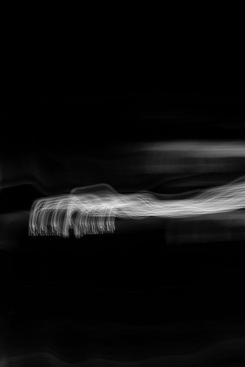 Free A dynamic abstract image featuring flowing white light trails against a black background. Stock Photo