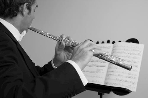 Grayscale Photo of a Man Playing the Flute 