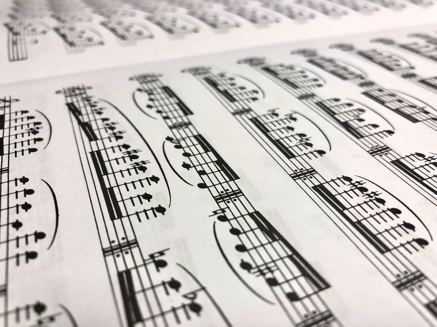 Close-up of sheet music showing curved slur marks connecting groups of notes