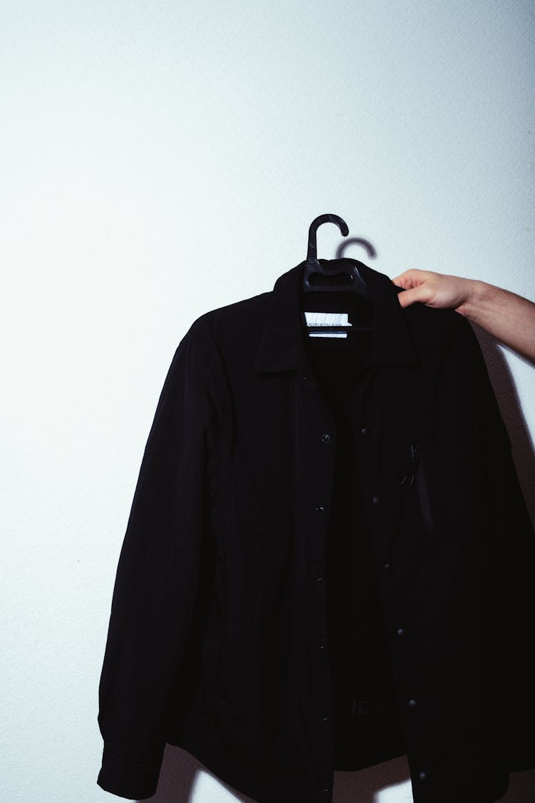 Person Holding Black Jacket With Hanger 