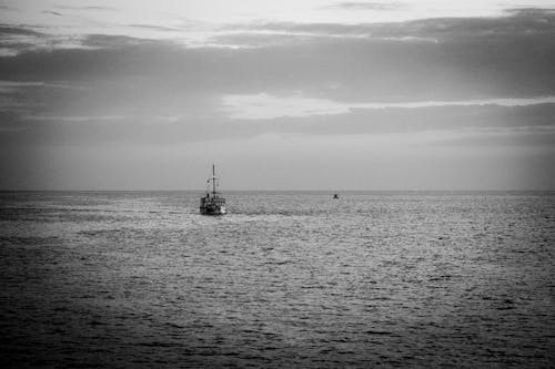Fishing Boat on Sea in Grayscale Photography