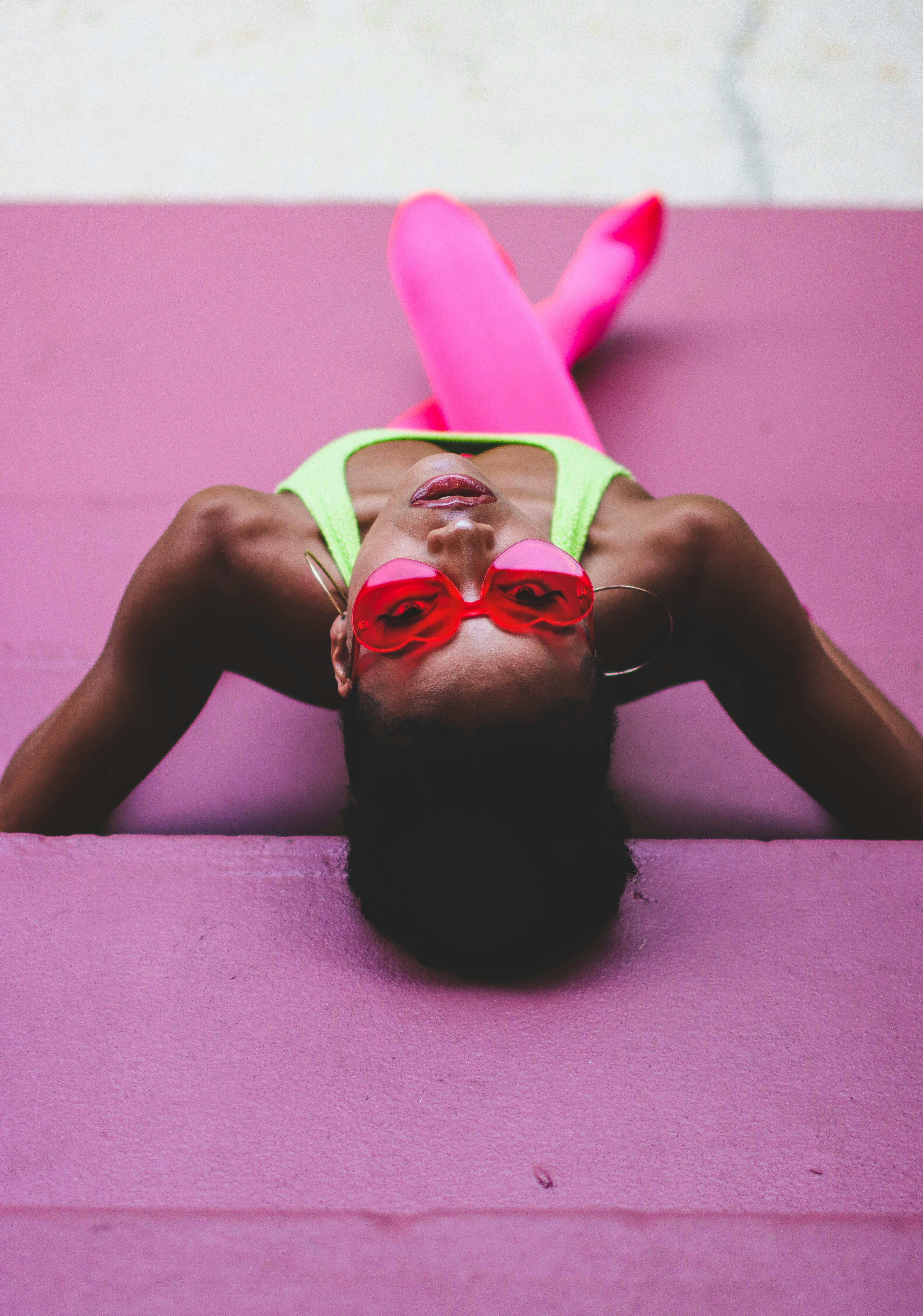 Vibrant portrait of a woman wearing pink sunglasses and neon clothes, on a colorful background in Orlando.