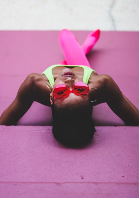 Vibrant portrait of a woman wearing pink sunglasses and neon clothes, on a colorful background in Orlando.
