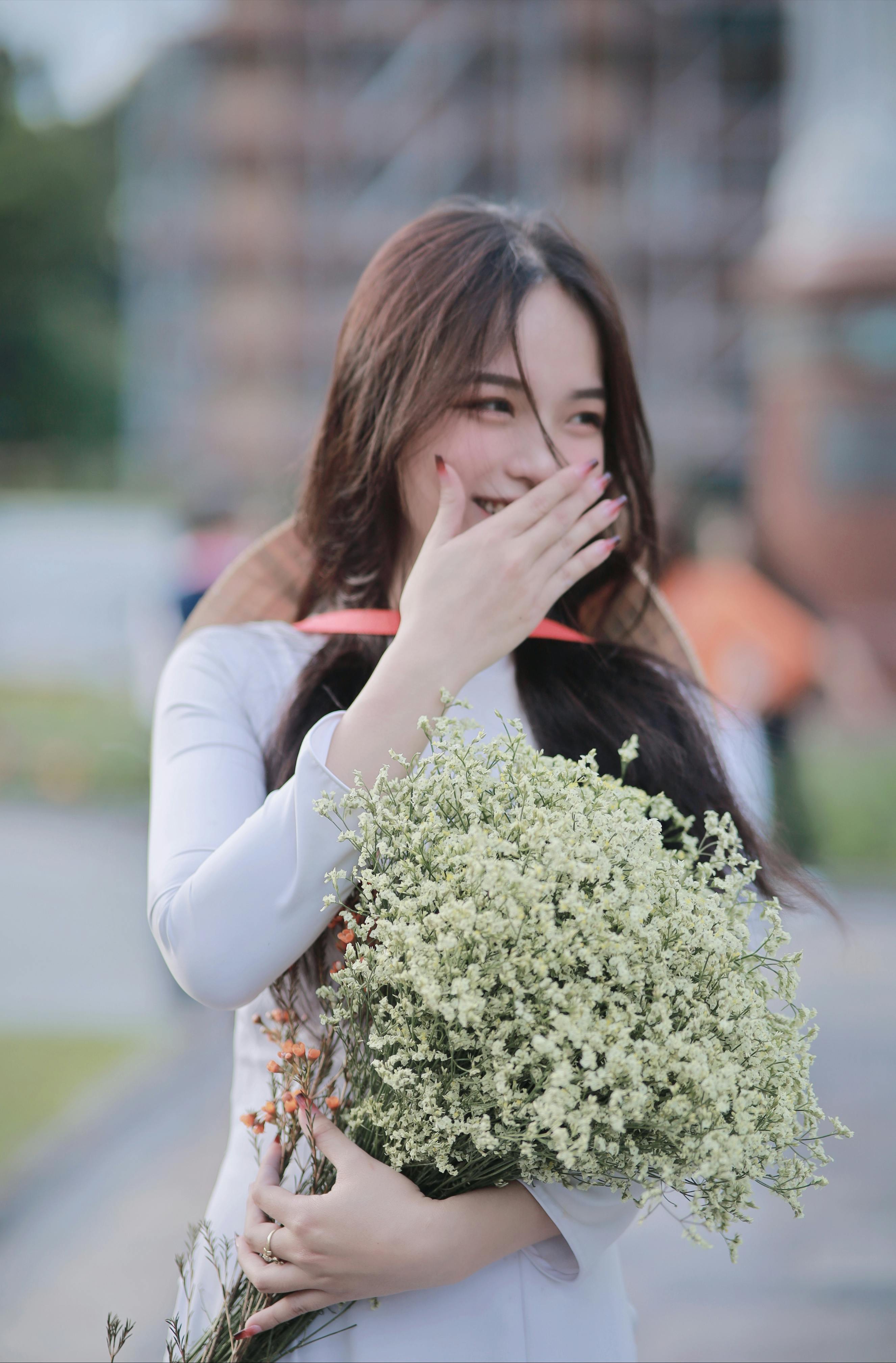 photo of a beautiful young woman wearing ao dai and holding a bouquet