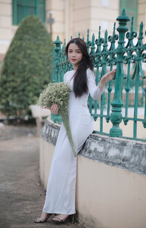 Young Woman in a Blue Dress Holding a Bunch of Flowers