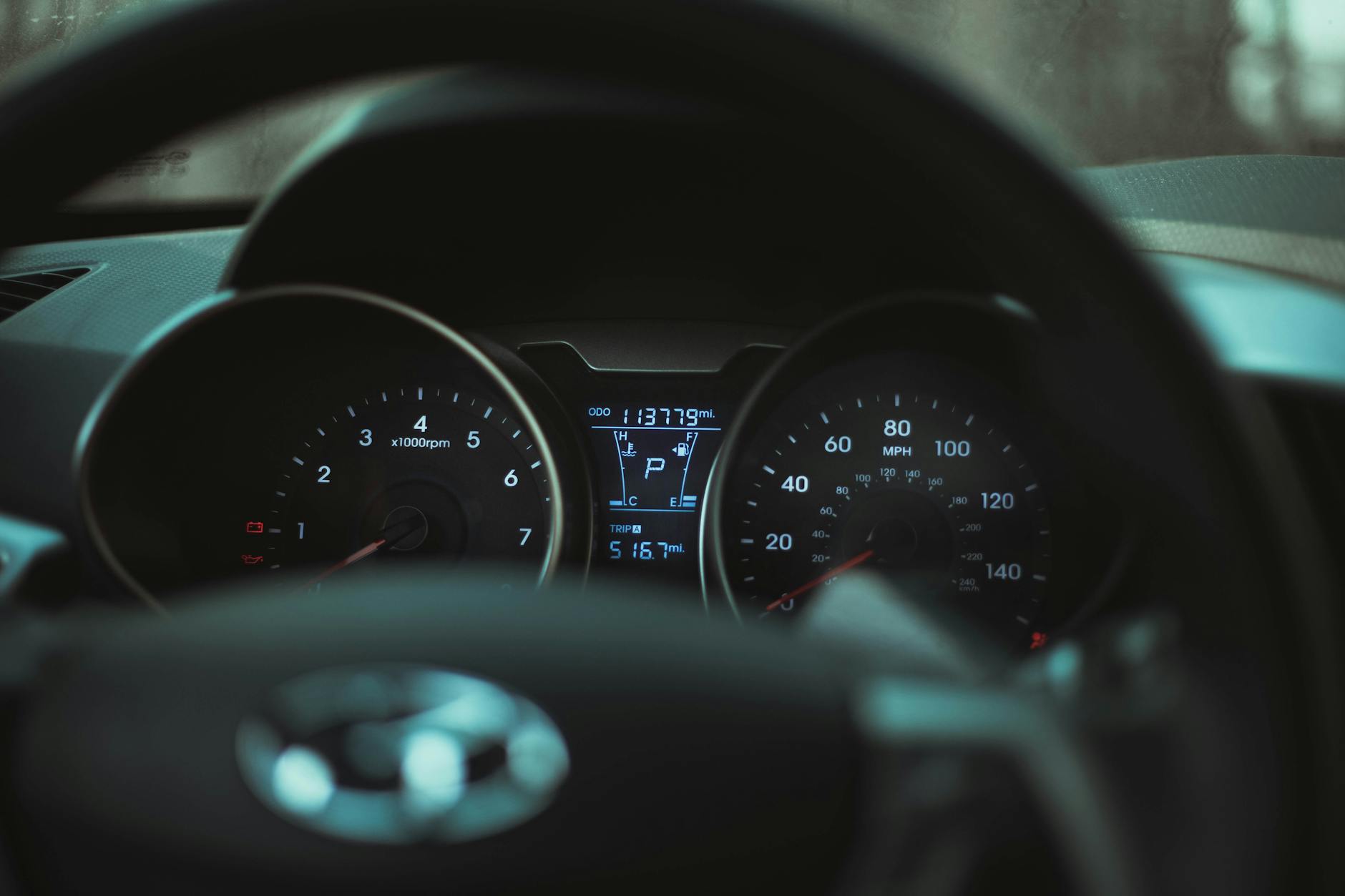 Focus on a car dashboard showing odometer and rev counter in dim light.