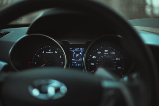 Focus on a car dashboard showing odometer and rev counter in dim light.