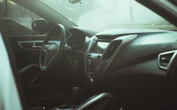 Close-up view of a car interior featuring a steering wheel and dashboard in soft ambient lighting.