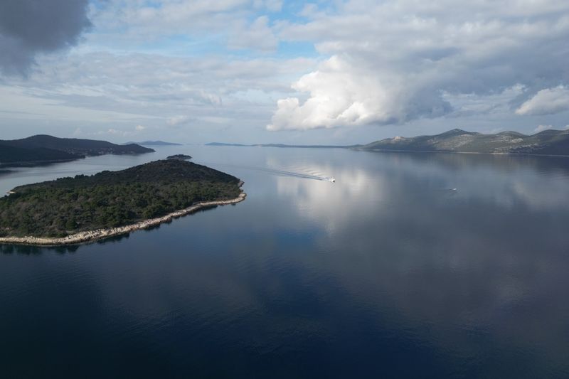 Serene aerial shot of Mali Iž island reflecting on the Adriatic Sea with a cloudy sky.