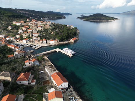 Scenic aerial view of Mali Iž, a picturesque coastal village in Croatia with red-roofed houses and turquoise waters.