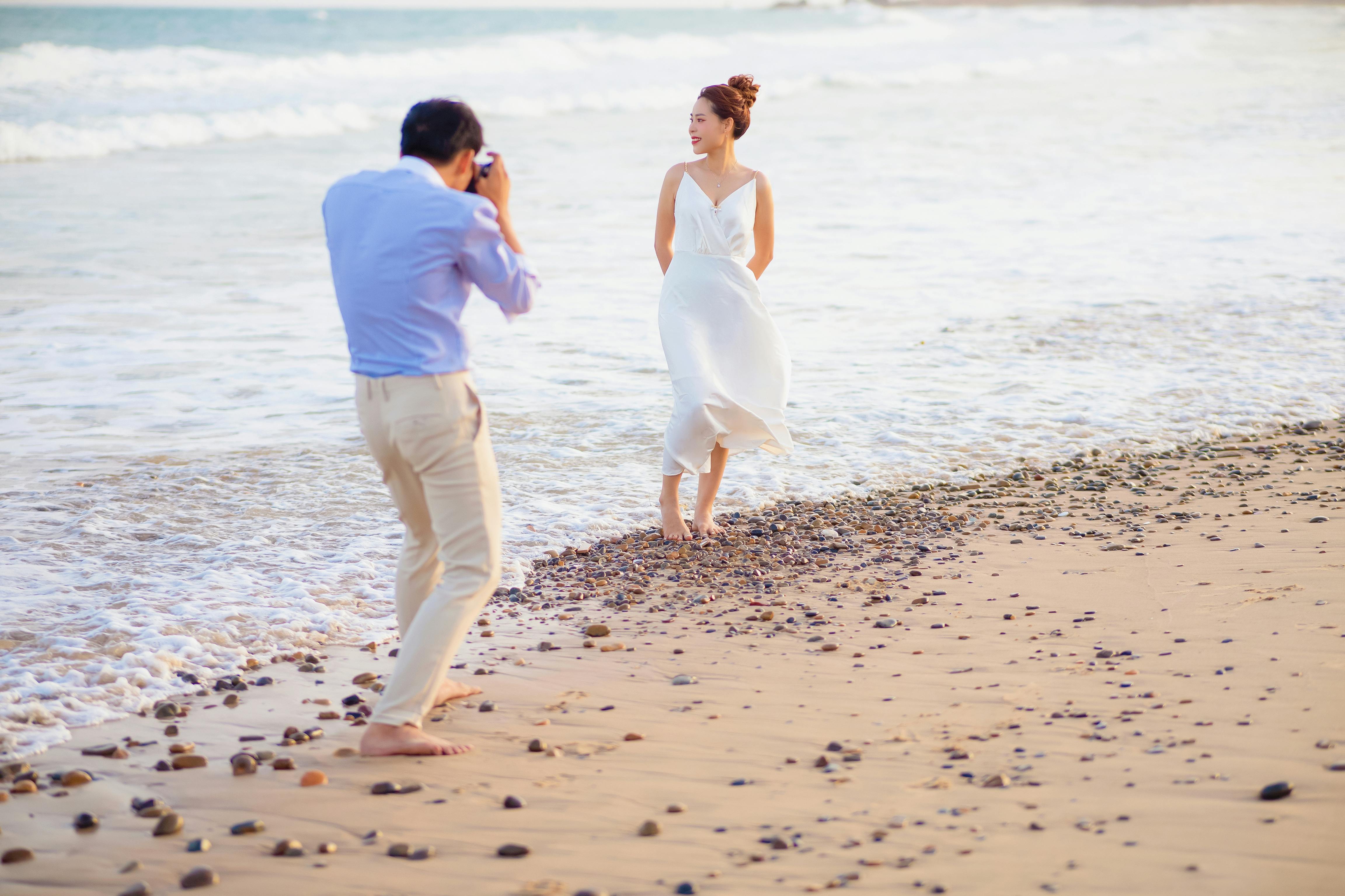 Free A photographer captures a woman posing on a sunny beach. Stock Photo