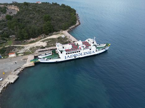 Stunning aerial view of Jadrolinija ferry docked at Mali Iž in Croatia, surrounded by lush greenery and blue sea.