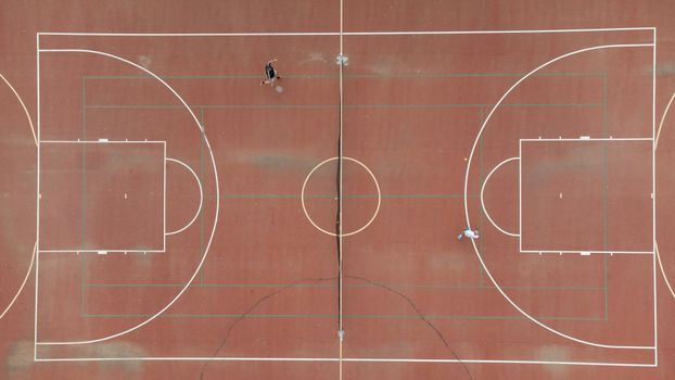 A drone shot of a tennis court with two players engaged in a game, taken from above.