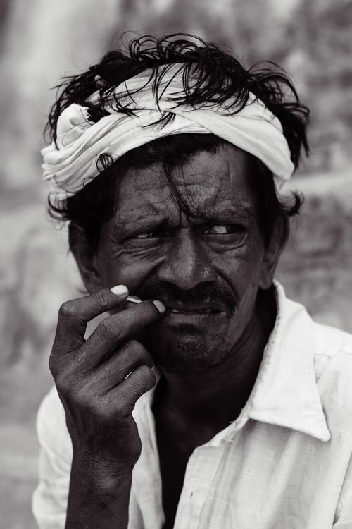 Free Captivating black and white portrait of a mature man in traditional attire, holding a toothpick with a pensive expression. Stock Photo