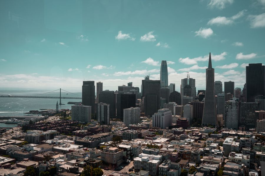 Wide aerial view of San Francisco's downtown skyline with the bay and surrounding neighborhoods visible under clear blue skies