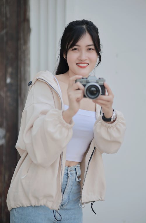 Young Woman Holding a Camera and Smiling 
