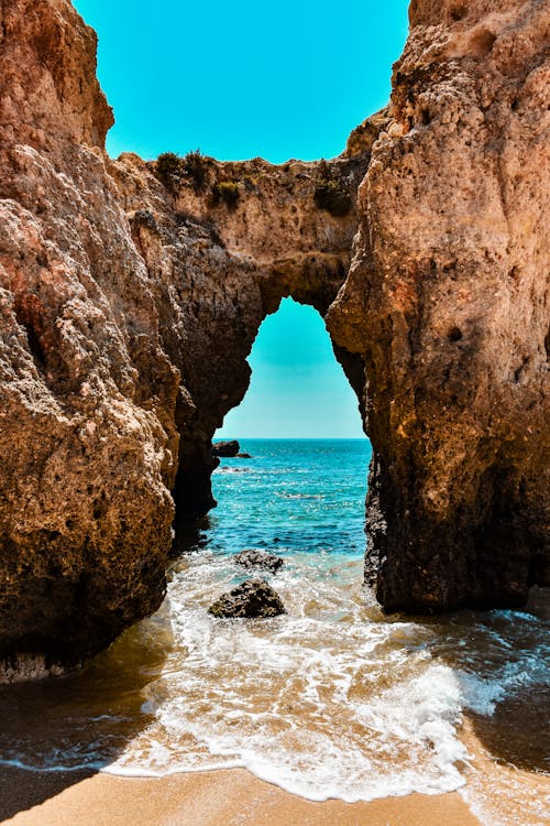бесплатная Фотография скальной формации у берега моря под голубым небом Стоковое фото