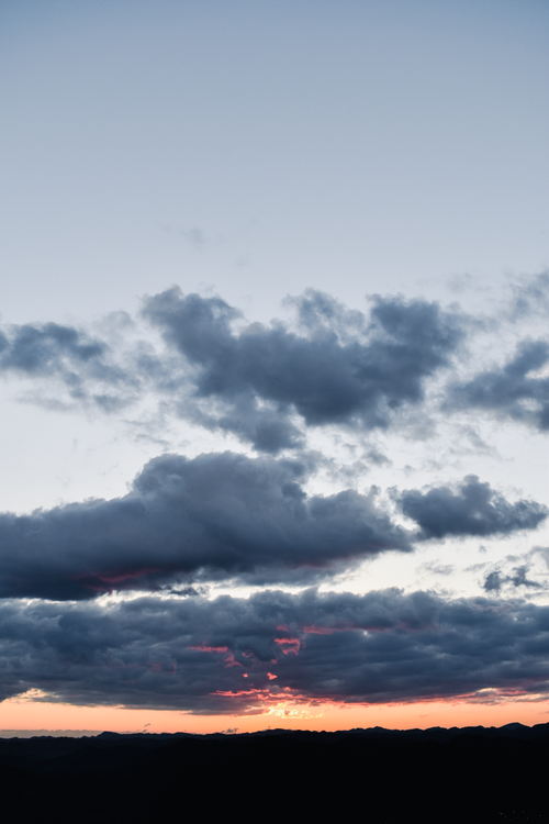 Free Beautiful sunset with dramatic clouds and a colorful sky creating a serene atmosphere. Stock Photo