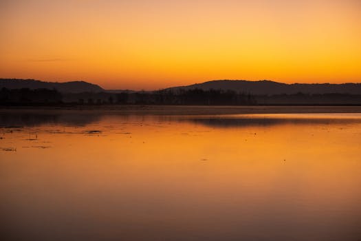 A tranquil sunrise over a calm lake in Minnesota, USA, with reflections and warm tones.