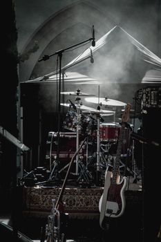 Dimly lit stage with drum kit and electric guitar ready for a live performance.