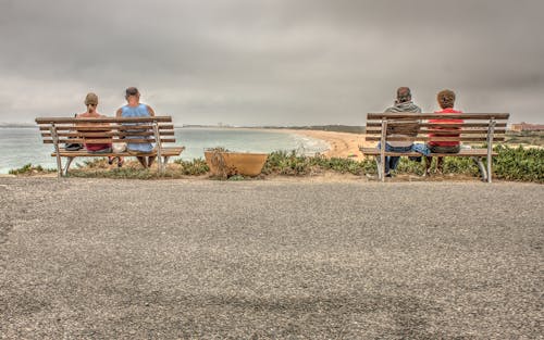 Free Two Couple Sitting on Bench Near Beach Stock Photo