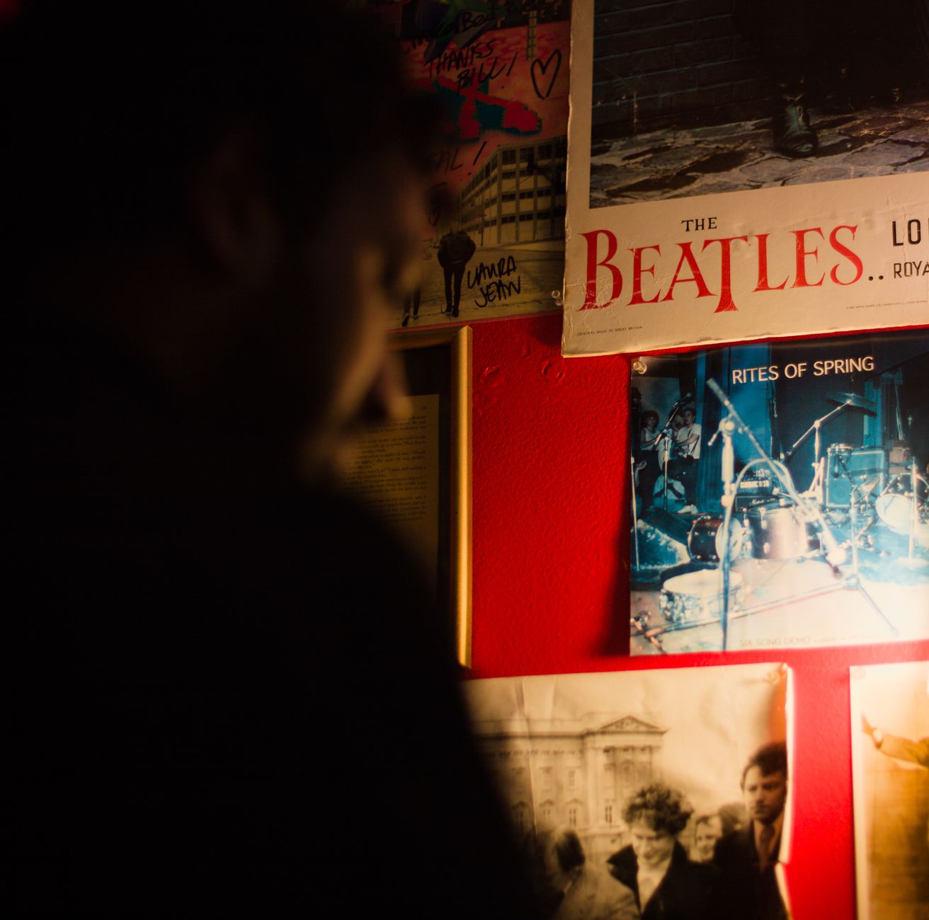 A moody scene featuring vintage music posters on a red wall with subtle lighting effects.