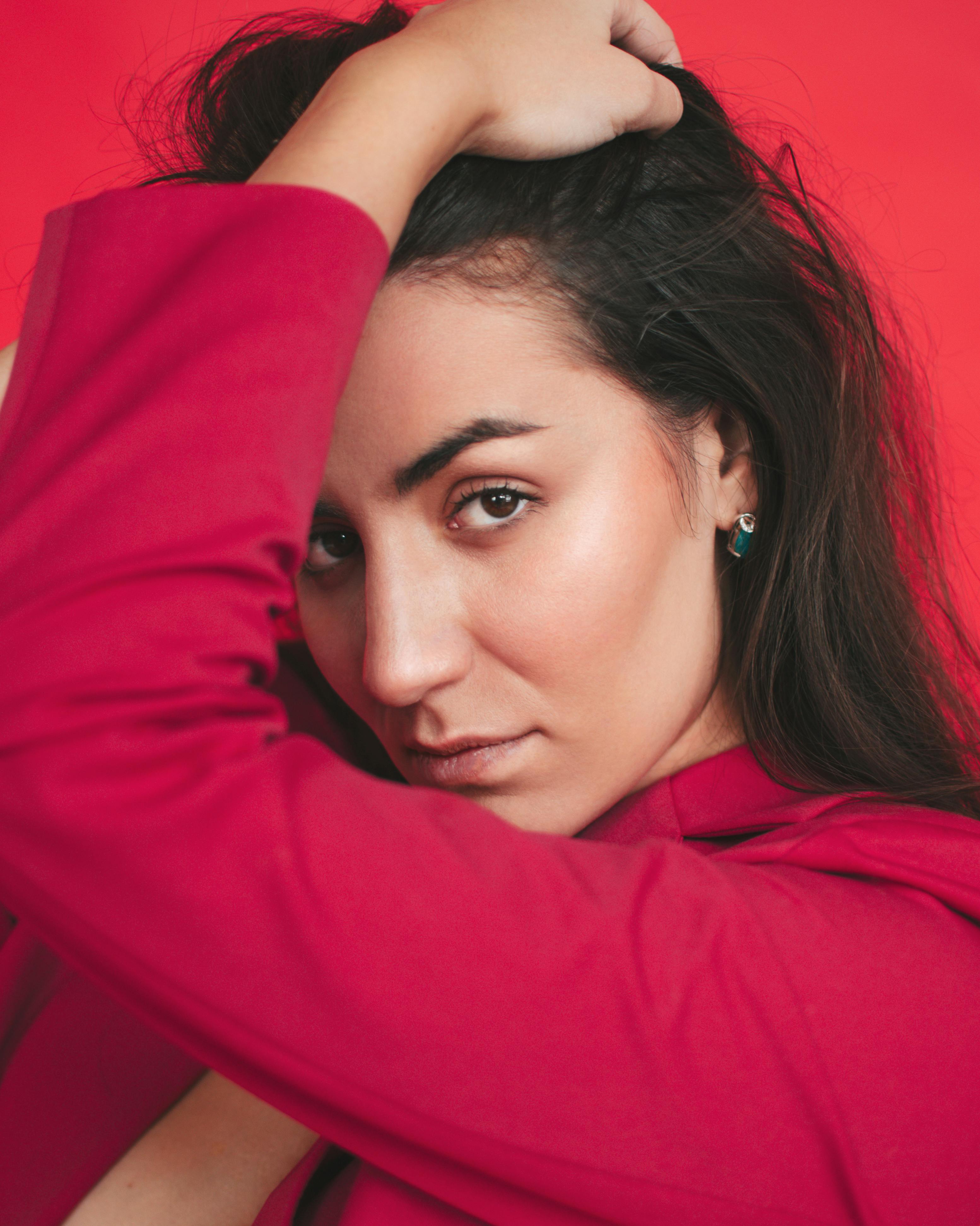 在工作室里，一位女士在大胆的红色背景下优雅地摆姿势的特写照片