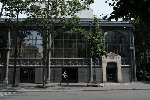 A woman walks past a historic building in Paris, showcasing classic architecture.