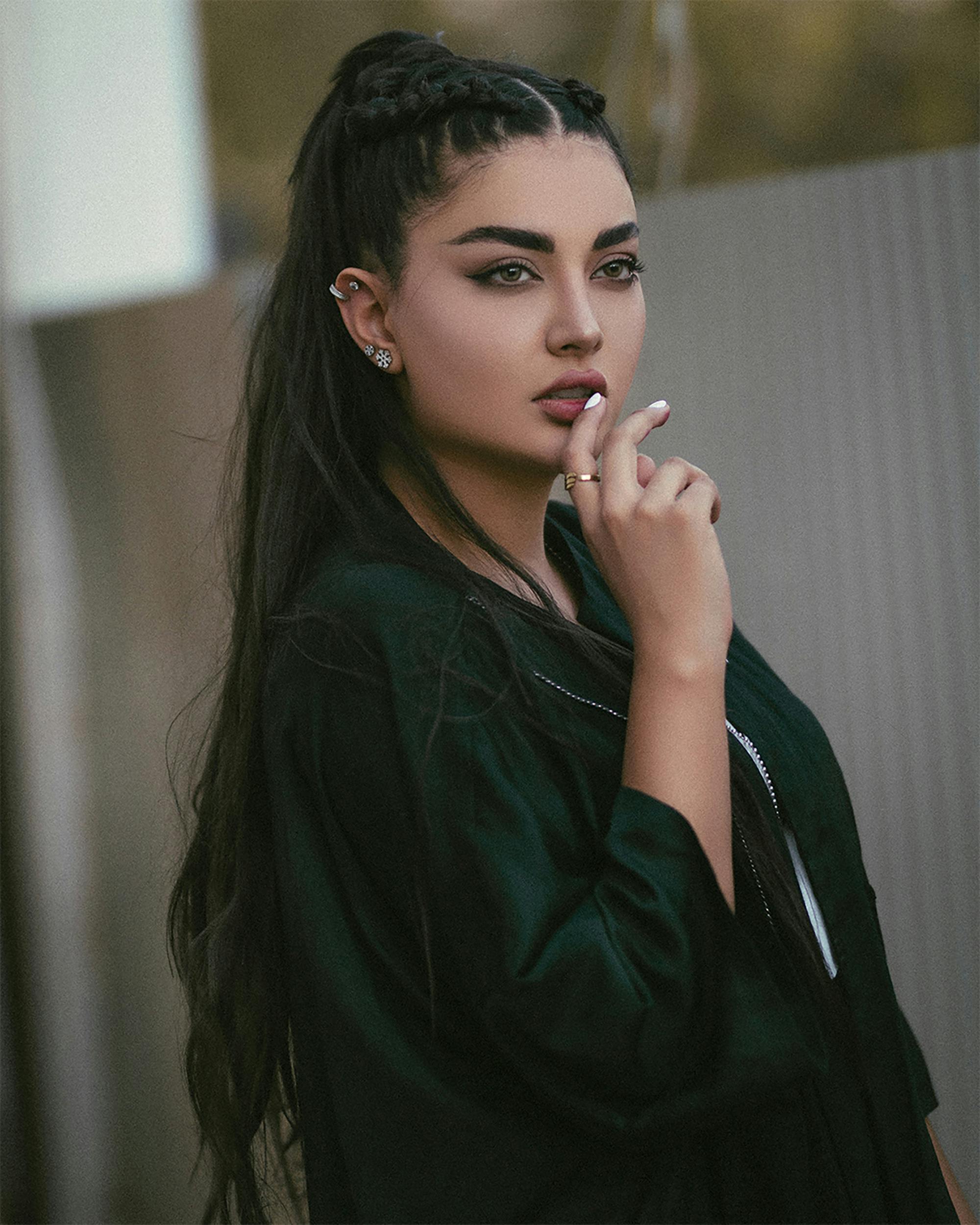 Stylish portrait of a young woman with braided hair and black attire, showcasing elegance and confidence.