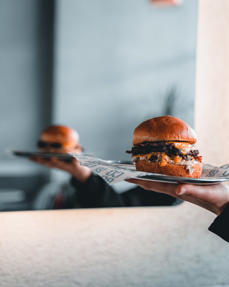 A Person Holding A Plate Of Cheeseburger