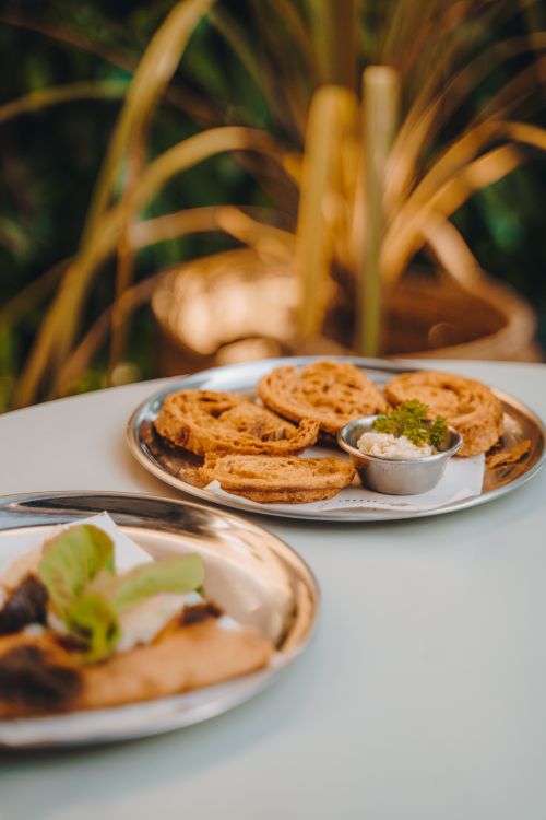 Free Crispy snack platter served with dip on a sunny outdoor table, perfect for appetizers. Stock Photo