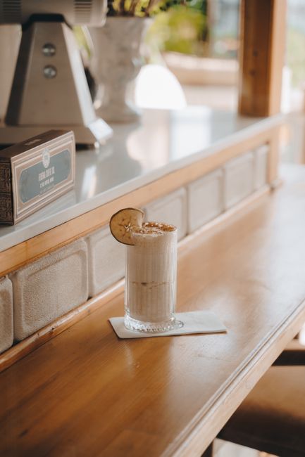 Close-up of an iced coffee with citrus slice on a sunlit wooden table.