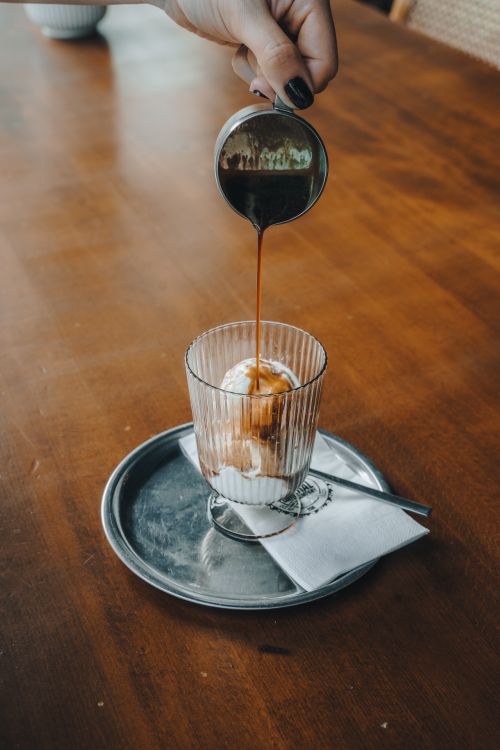 Free Close-up of an ice cream parfait in a glass with coffee being poured over it, creating a delectable dessert moment. Stock Photo