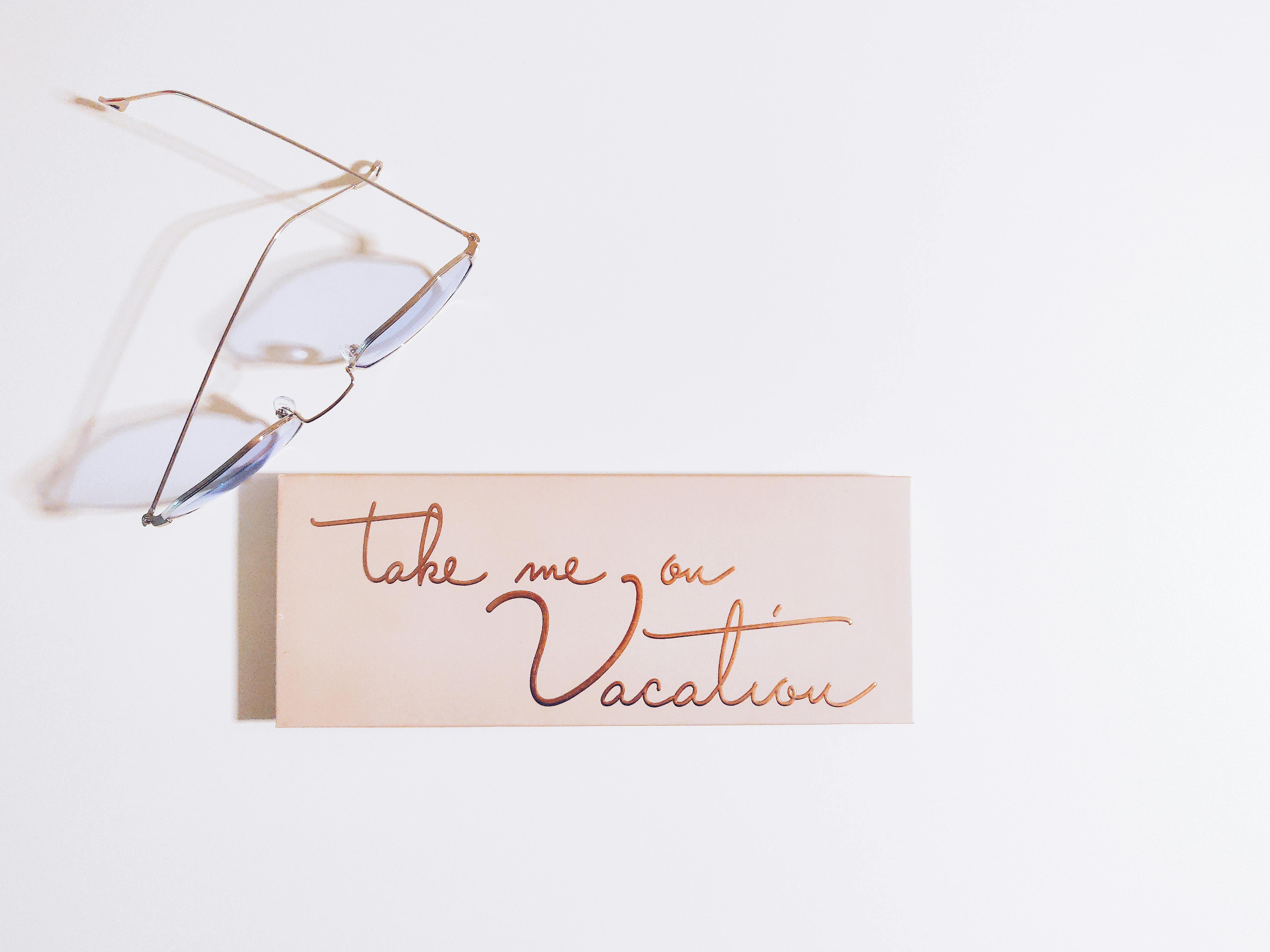 Minimalist image with eyeglasses and vacation-themed note, perfect for travel inspiration.